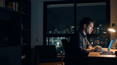 Doctor studying at night on a laptop, Brazilian city in the background